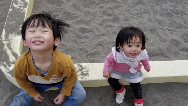 砂場のわくに座る幼児2人